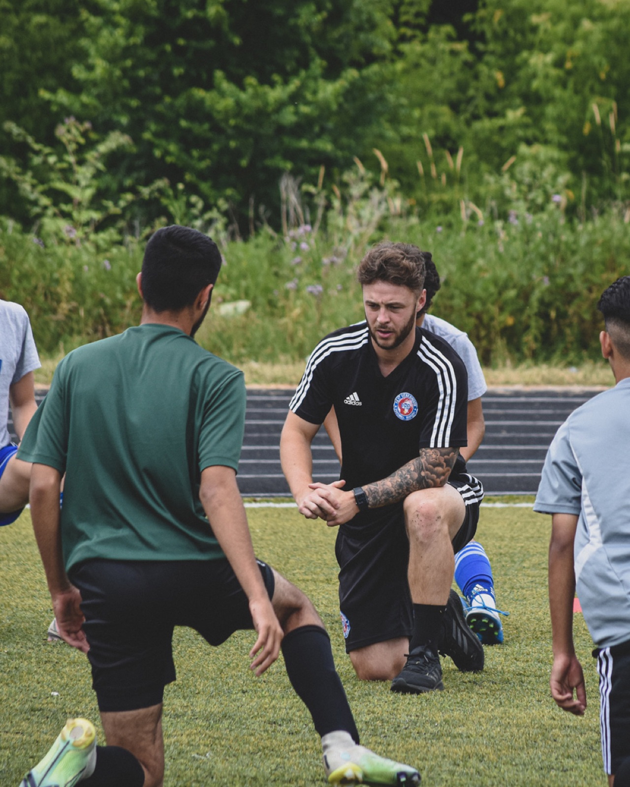 Young coach leading a session with cones and bibs on a club pitch
