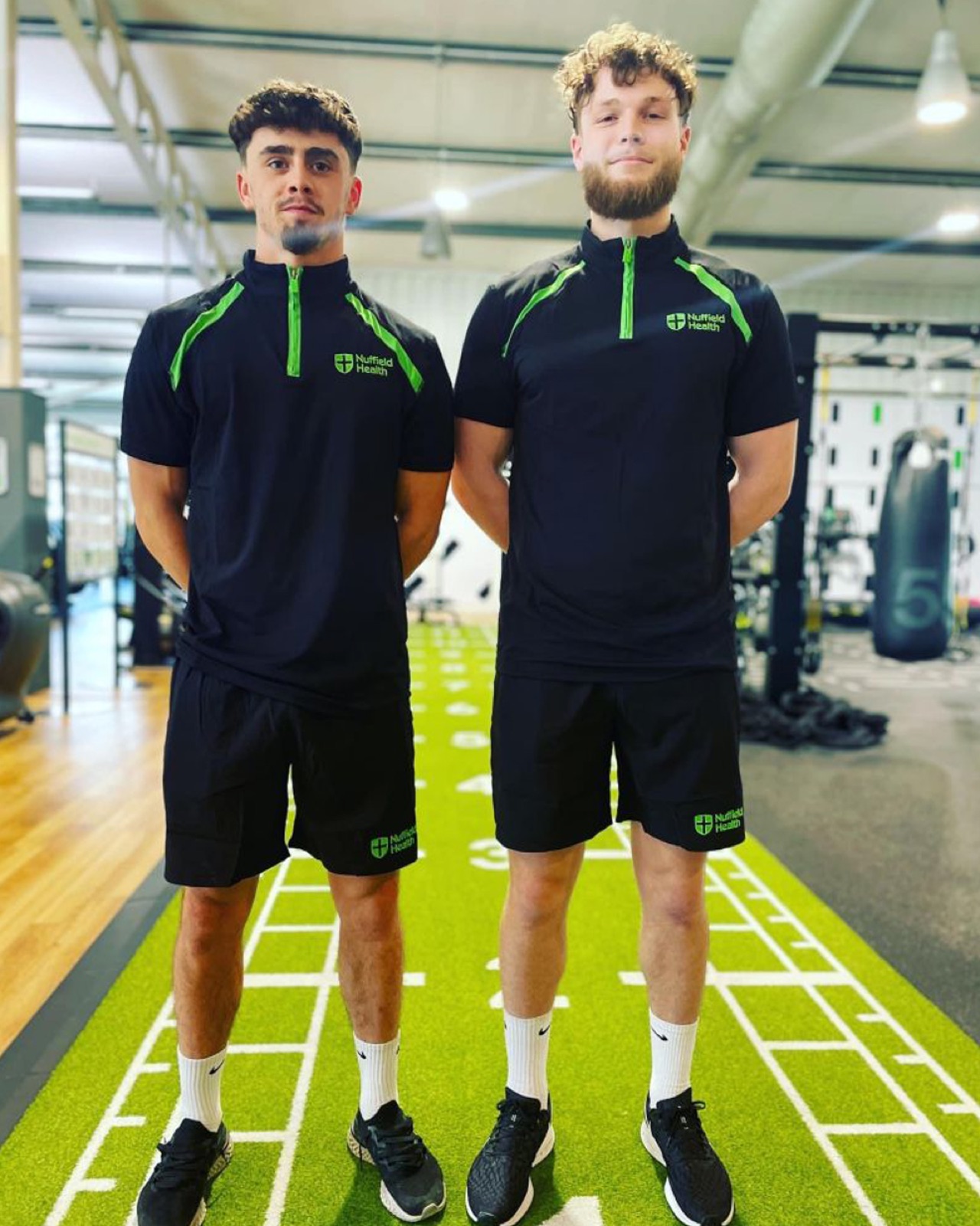 Personal trainer guiding a client through a strength session in a modern gym