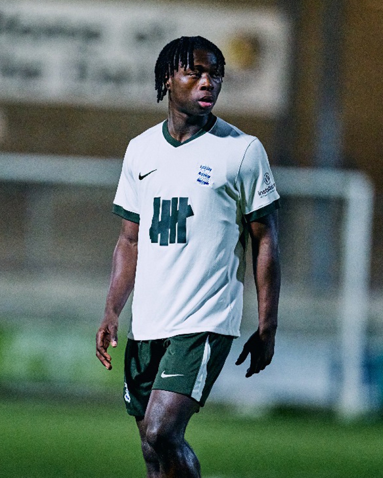 Semi-professional player driving forward with the ball under floodlights
